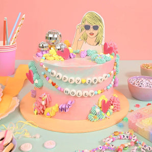 Taylor Swift Cake with pastel icing, disco balls, friendship bracelet decor, and piped details by Crumbs & Doilies